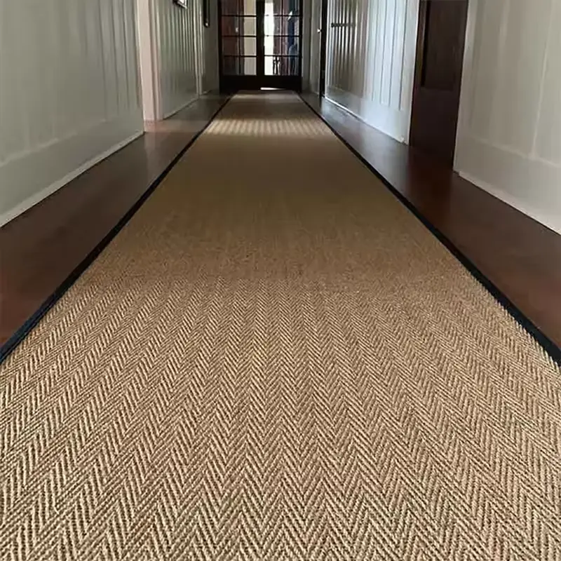 herringbone-textured sisal carpet runner with a black border on dark hardwood floors